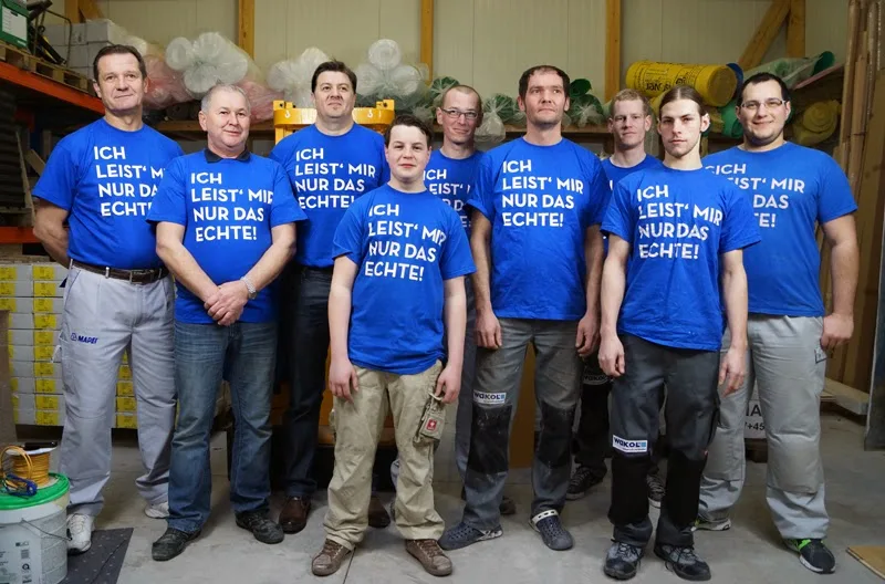 Zehn Facharbeiter in blauen Boden-Karner-Shirts im Lager